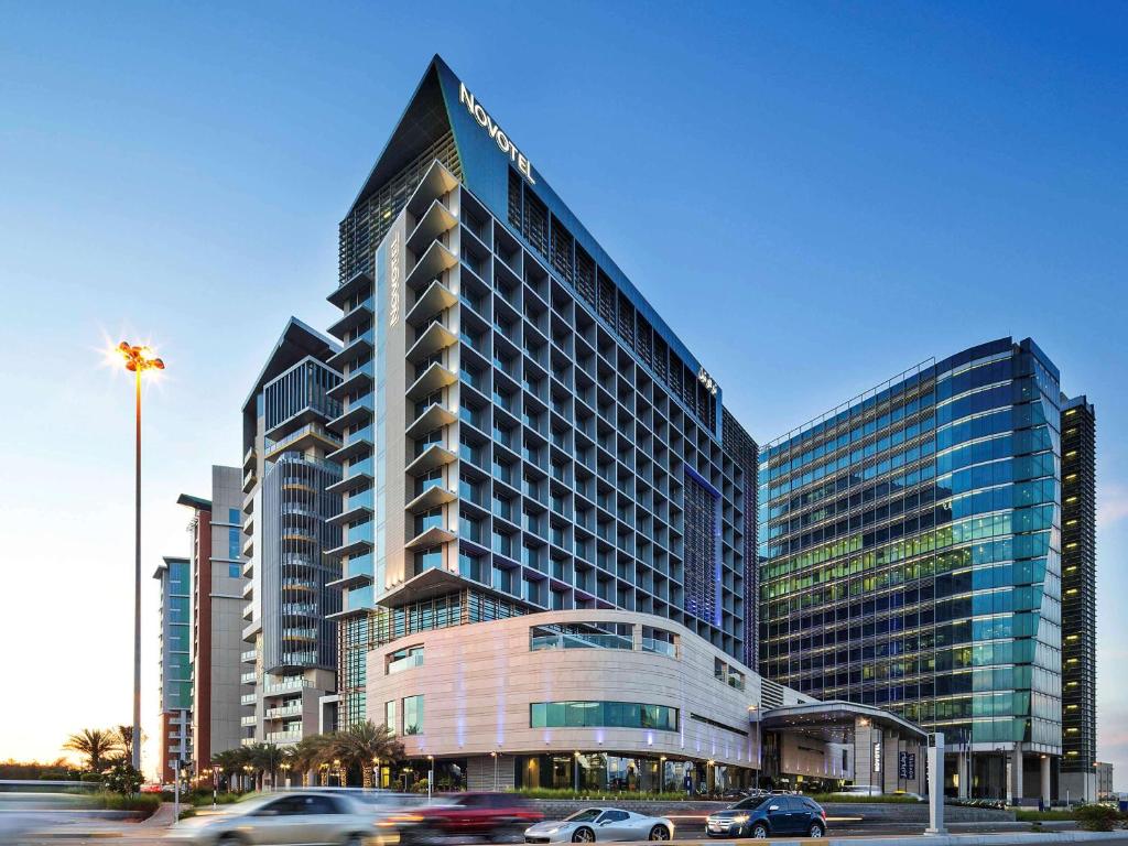 ein hohes Gebäude mit Autos davor in der Unterkunft Novotel Abu Dhabi Al Bustan in Abu Dhabi