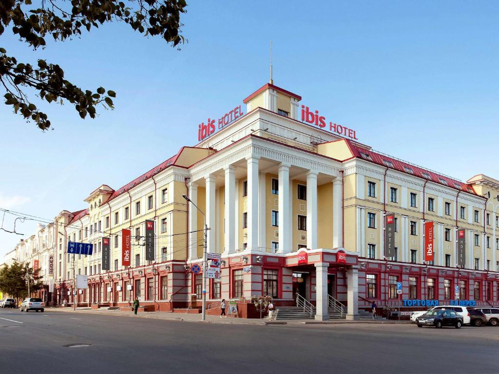 ibis Sibir Omsk Hotel في أومسك: مبنى ابيض كبير باللون الاحمر والابيض