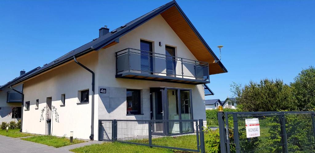 a white house with a balcony and a fence at Dom Wakacyjny Jastrzębia Góra in Jastrzębia Góra