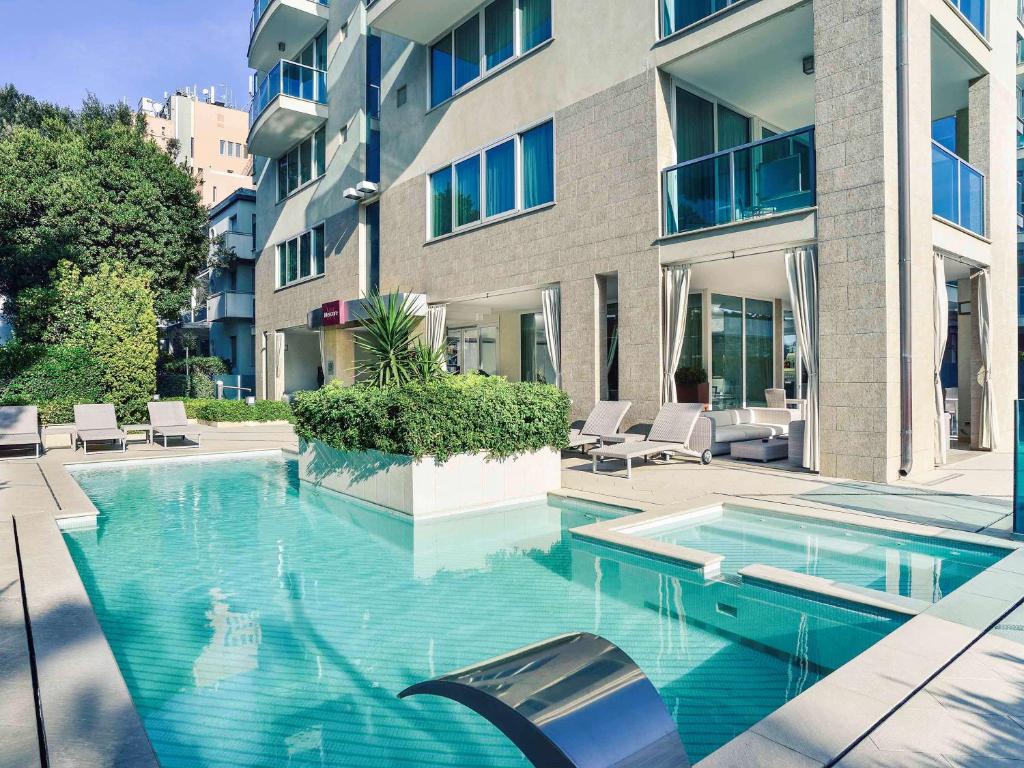 une piscine en face d'un bâtiment dans l'établissement Mercure Hotel Rimini Artis, à Rimini