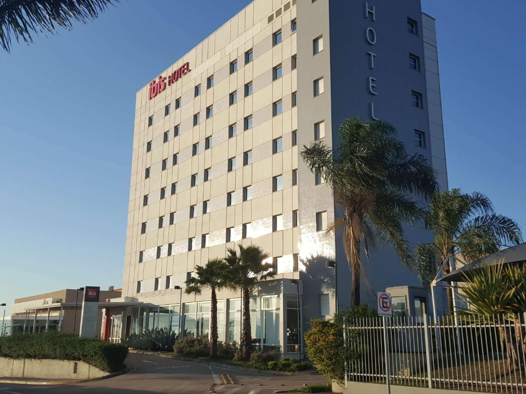 a hotel building with palm trees in front of it at ibis Itu Plaza Shopping in Itu