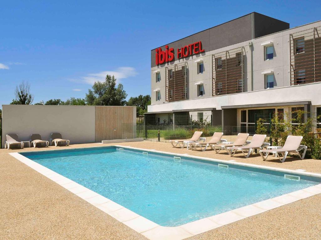 a swimming pool in front of a building with a hotel at ibis Istres Trigance in Istres