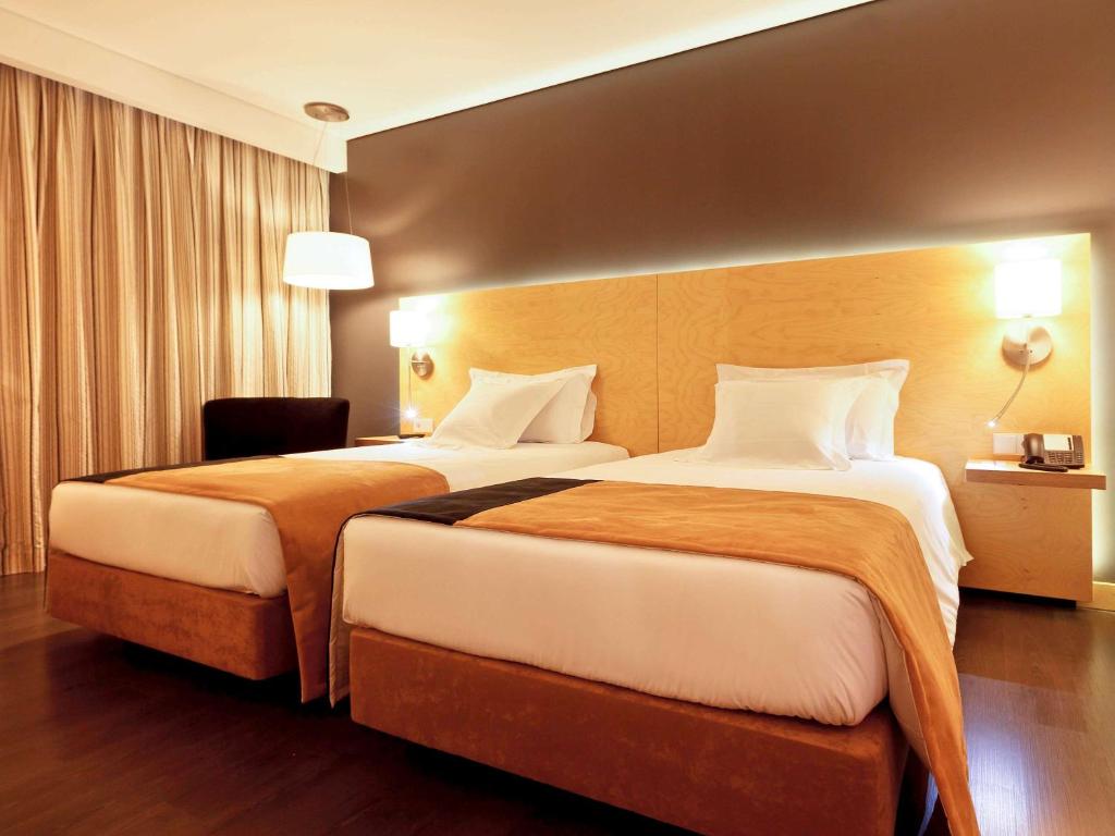 a hotel room with two beds and two lamps at Hotel Mercure Braga Centro in Braga