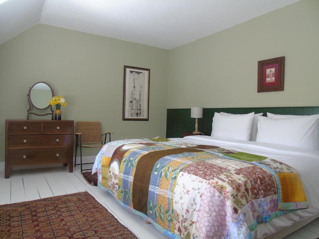 a bedroom with a large bed and a dresser with a mirror at Thistle Cottage, CrannachCottages in Garve