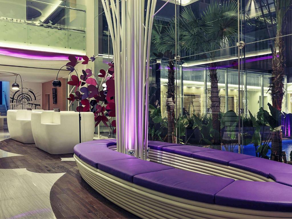 a lobby with purple benches and plants in a building at Mercure Jakarta Sabang in Jakarta