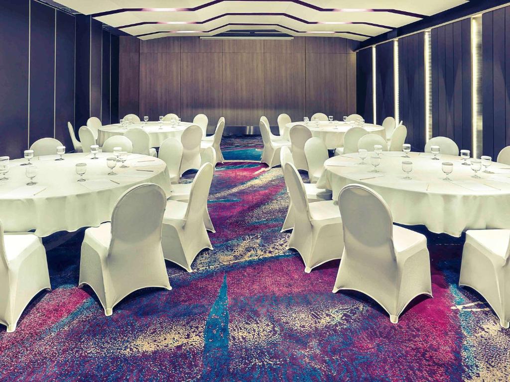 a conference room with white tables and white chairs at Mercure Jakarta Sabang in Jakarta