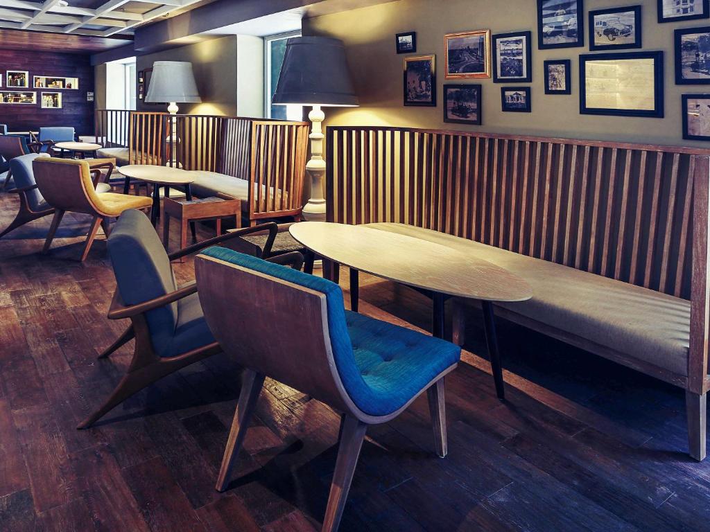 a restaurant with tables and chairs and a bench at Mercure Jakarta Sabang in Jakarta