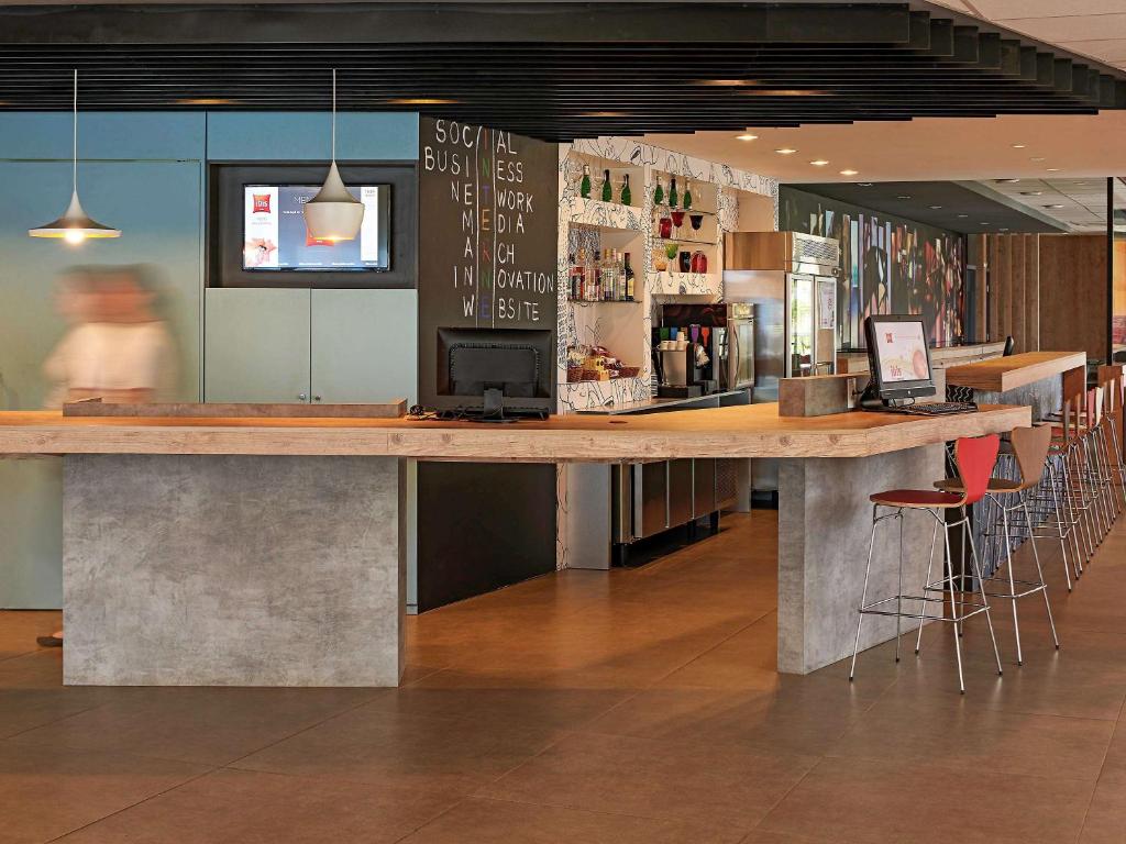 a large wooden bar in a restaurant with bar stools at ibis Londrina Shopping in Londrina