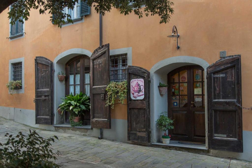 um edifício laranja com portas de madeira e vasos de plantas em Antica Casa Dei Rassicurati em Montecarlo
