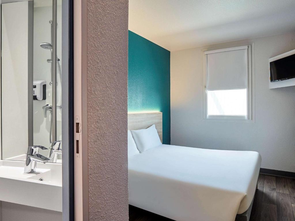 ein Badezimmer mit einem weißen Bett und einem Waschbecken in der Unterkunft hotelF1 Thonon Les Bains Est in Marin