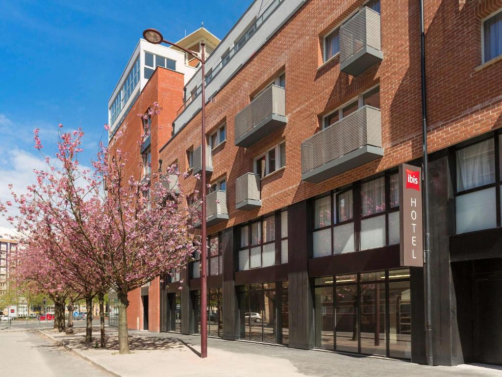 een rood bakstenen gebouw met een boom ervoor bij ibis Lille Centre Grand Palais in Lille