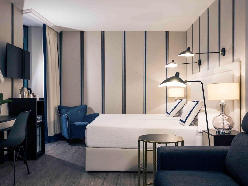 a hotel room with a bed and a couch and a table at Hotel Mercure Jardines de Albia in Bilbao