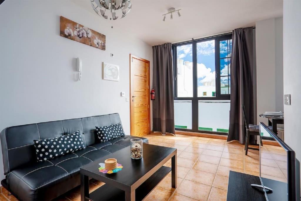 Una sala de estar con un sofá negro y una mesa. en Arrecife, en Arrecife