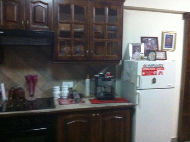 a kitchen with a white refrigerator and wooden cabinets at Zakos Court Apartments in Larnaca