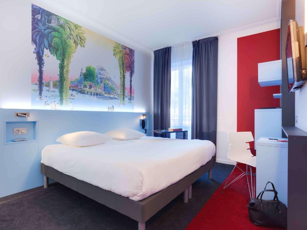 - une chambre avec un lit et une peinture de palmiers dans l'établissement ibis Styles Nantes Centre Gare, à Nantes