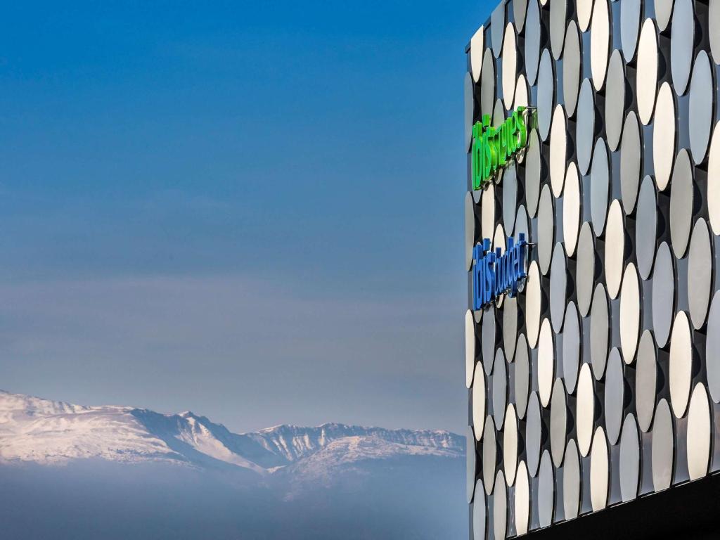 d'un bâtiment avec des montagnes en arrière-plan dans l'établissement ibis Styles Geneve Palexpo Aeroport, à Genève