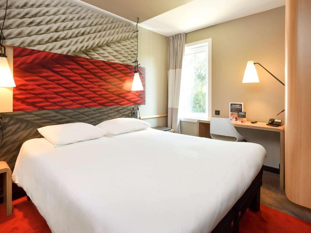 una camera d'albergo con un grande letto bianco e una finestra di Ibis Brussels Erasmus a Bruxelles