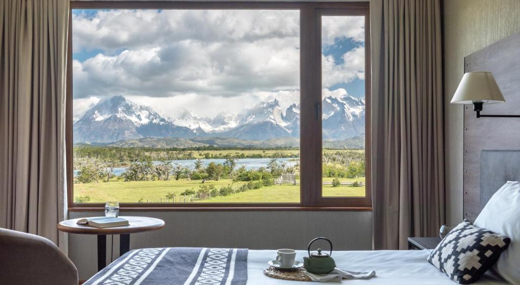 a bedroom with a large window with a view of mountains at Río Serrano Hotel + Spa in Torres del Paine