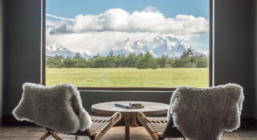 a room with two chairs and a table and a window at Río Serrano Hotel + Spa in Torres del Paine