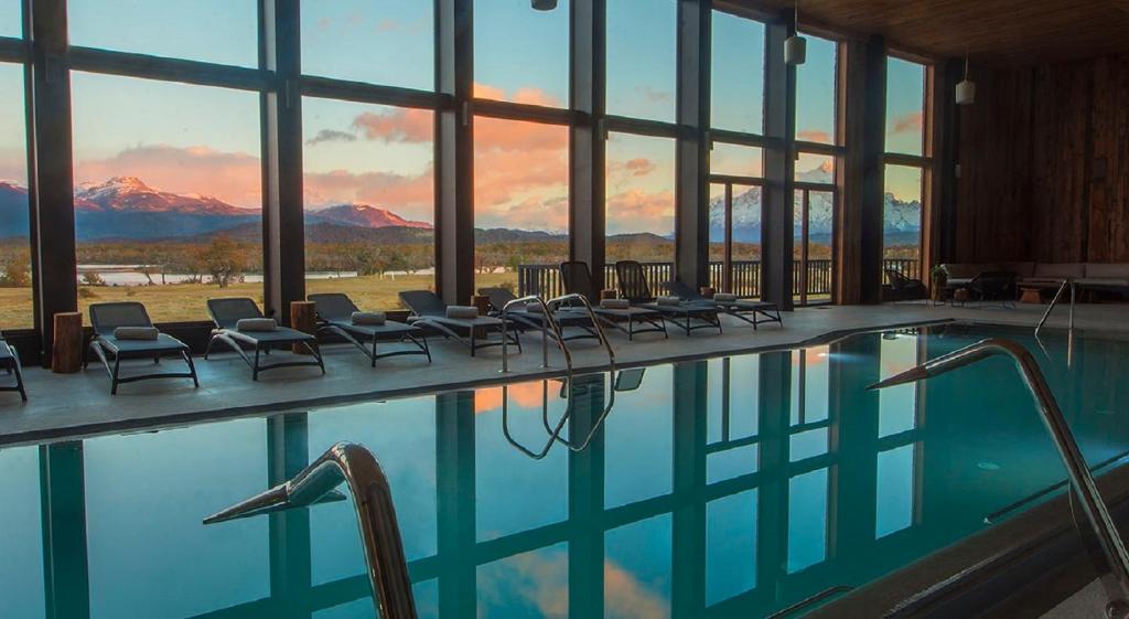 a swimming pool with chairs and a view of mountains at Río Serrano Hotel + Spa in Torres del Paine