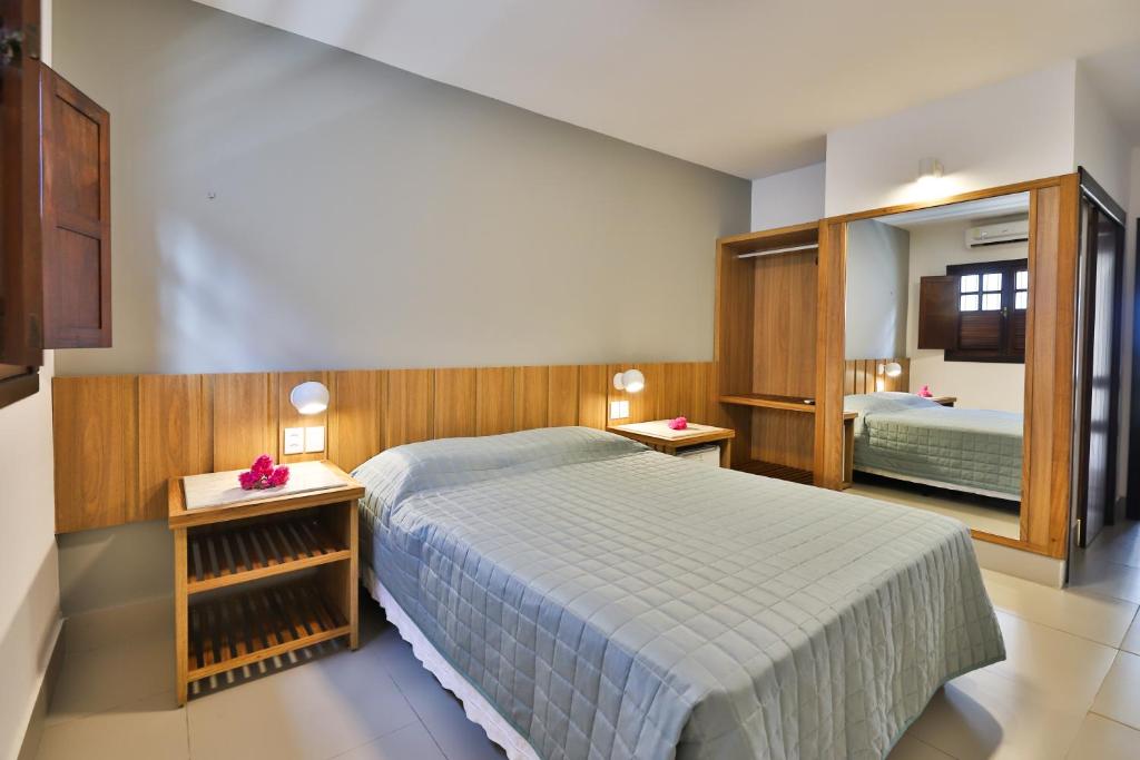 een slaapkamer met een groot bed en een spiegel bij Pousada da Ladeira in Pipa