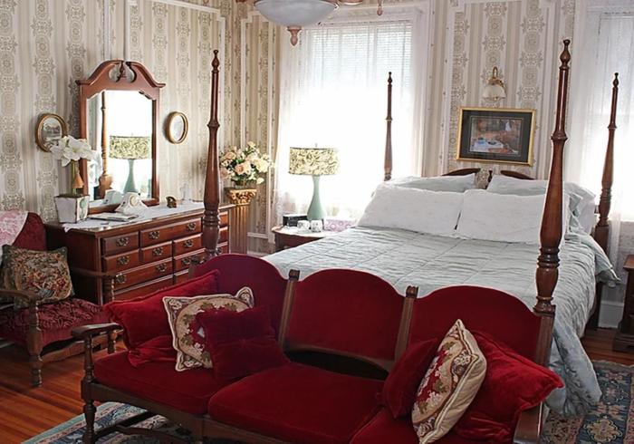 een slaapkamer met een bed, een bank en een spiegel bij Port City Guest House in Wilmington