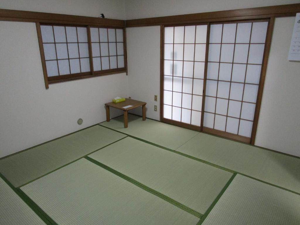 池袋駅まで徒歩15分 畳の家 في طوكيو: غرفة فارغة ذات أرضيات خضراء ونوافذ