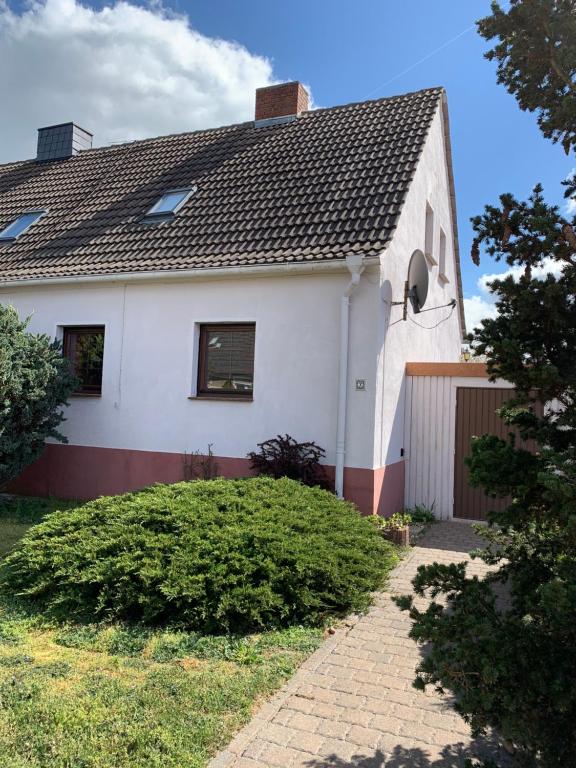 uma casa branca com um telhado preto em Gemütliches Ferienhaus mit Garten em Oranienbaum-Wörlitz