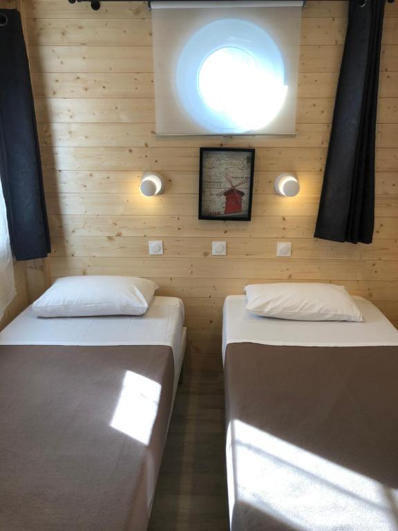 Ce lit se trouve dans un dortoir doté de murs en bois et d'une fenêtre. dans l'établissement Villa Liberté Verdun, à Villejuif