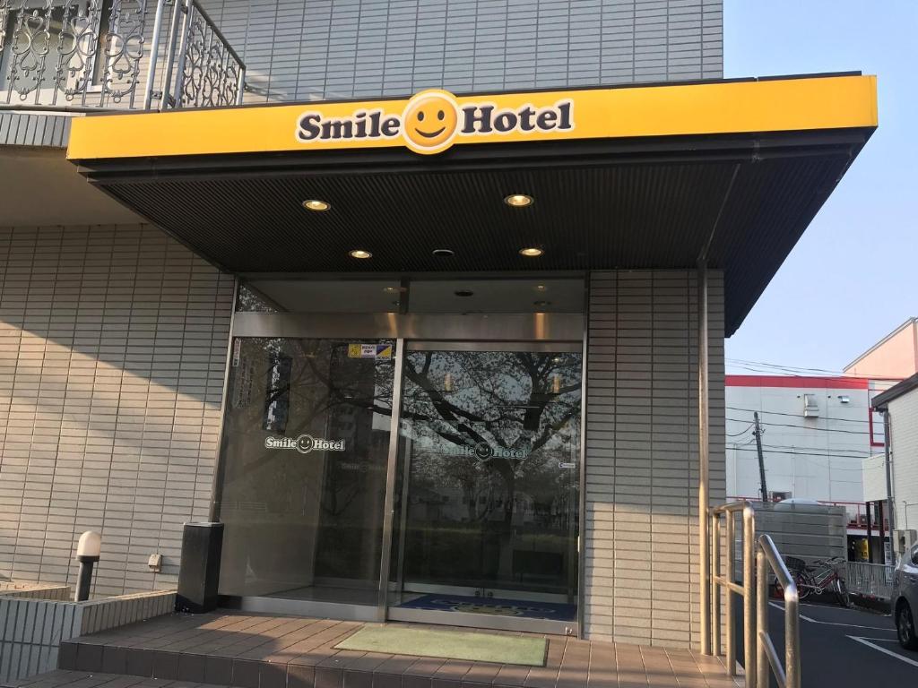 a smiley hotel sign on the front of a building at Smile Hotel Mito in Mito