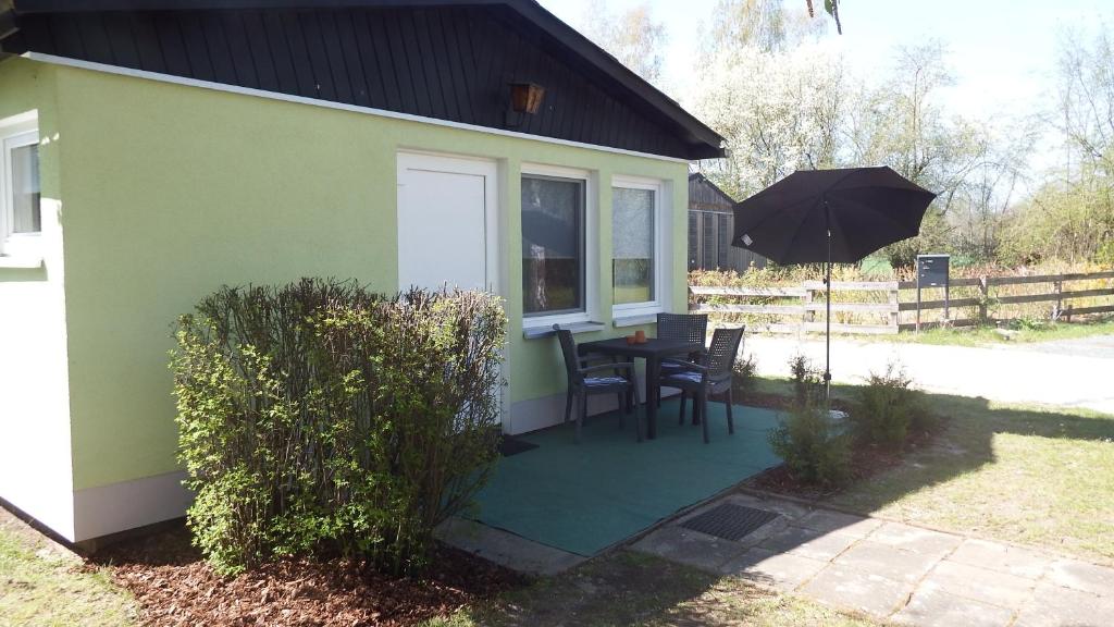 ein kleines grünes Haus mit einem Tisch und einem Sonnenschirm in der Unterkunft Ferienhäuser Stübgen in Burg