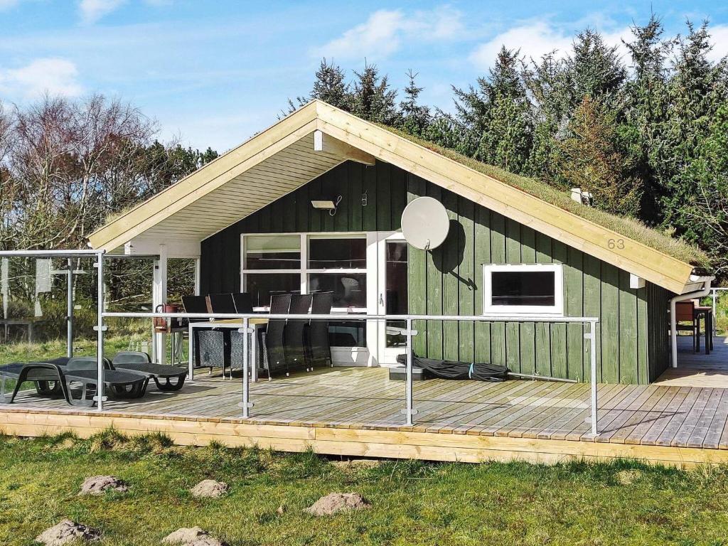 uma casa verde com um deque com um micro-ondas em 6 person holiday home in Pandrup em Rødhus