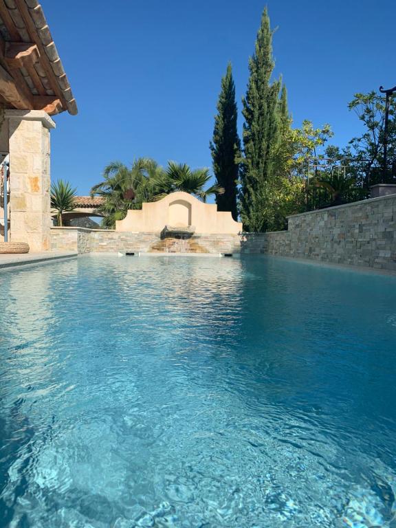 una piscina con acqua blu di fronte a una casa di Les 4 éléments a Tourrettes-sur-Loup