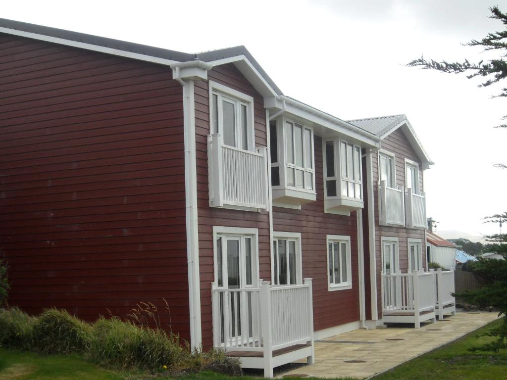 ein rotes Haus mit weißen Balkonen darauf in der Unterkunft Malvina House Hotel in Stanley