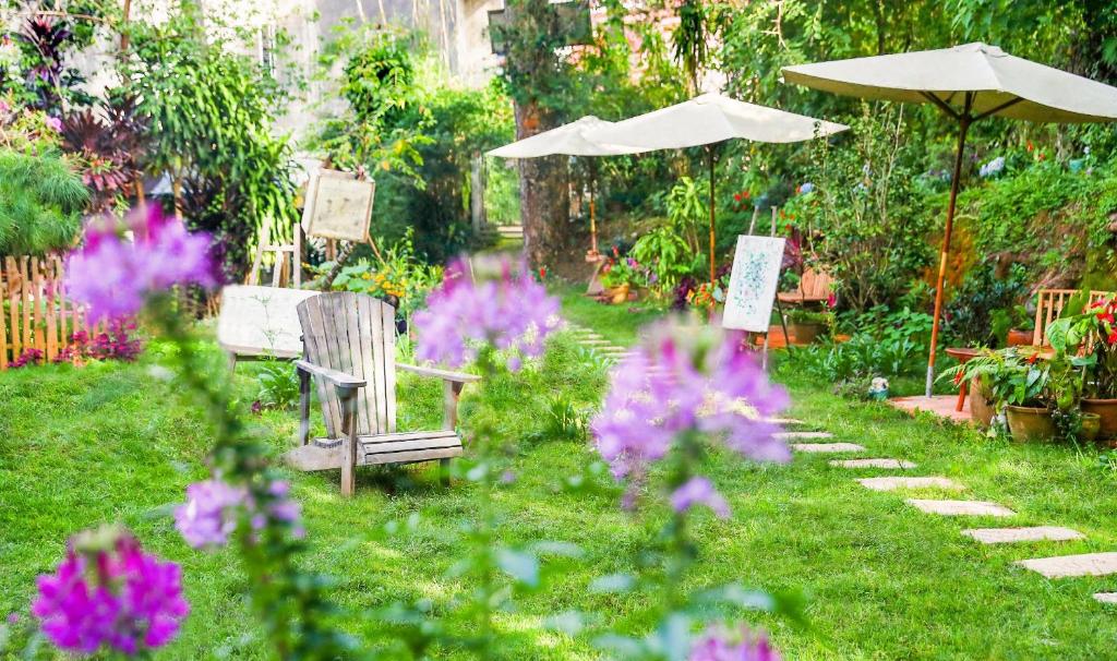a garden with a bench and an umbrella and flowers at Stop and Go Boutique Hotel in Da Lat