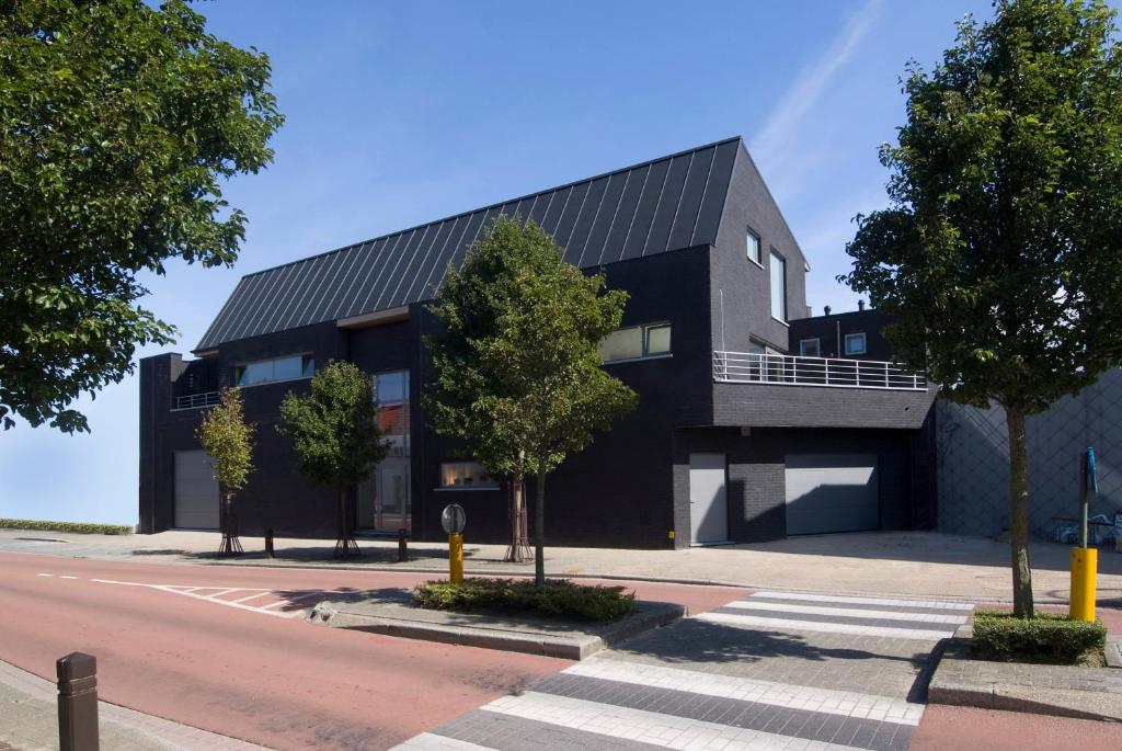 un edificio negro con árboles delante de él en WELLNESSLOFT, en De Haan