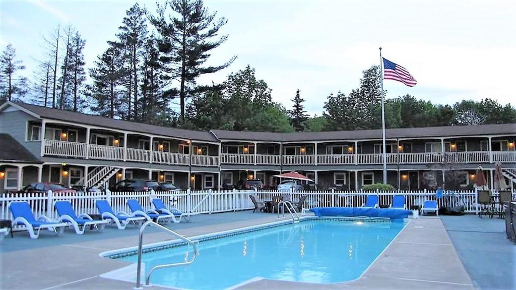 a resort with a swimming pool and chairs and a building at Mt. Madison Inn & Suites in Gorham