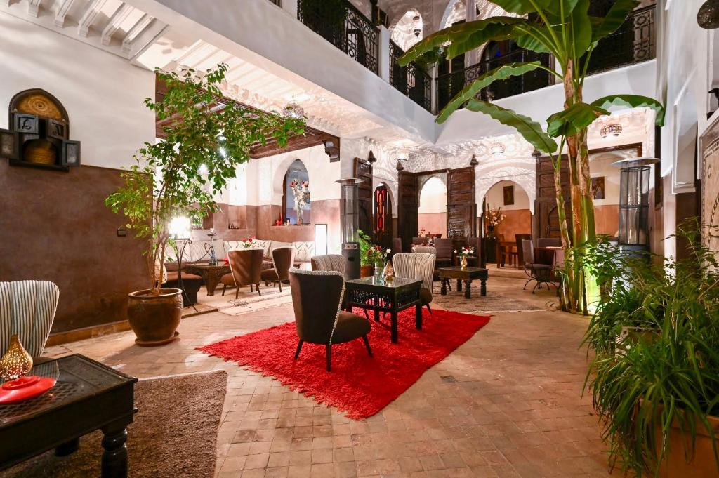 a room with a table and chairs and a red rug at Riad Aya in Marrakesh