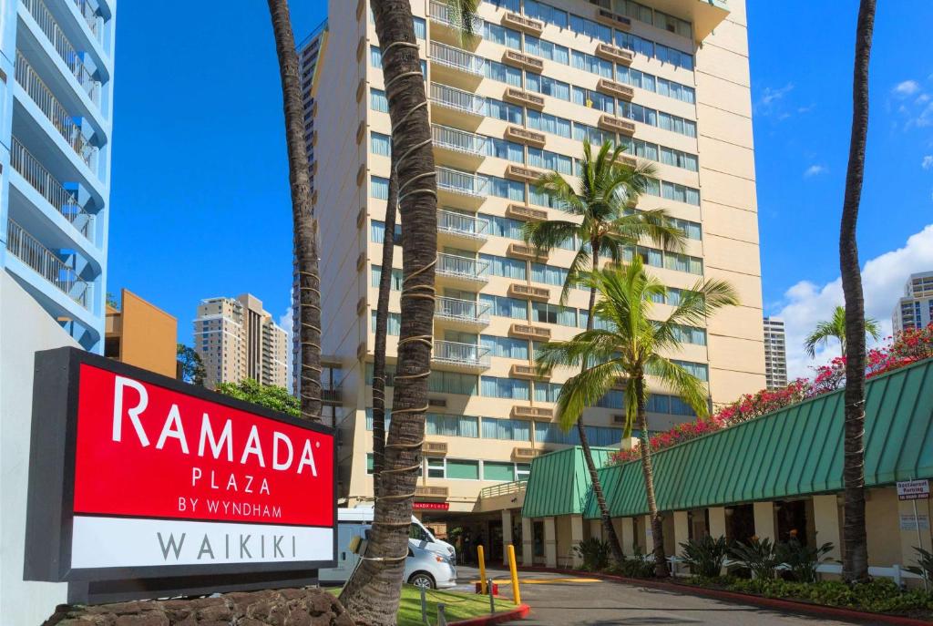 a sign for a hotel in front of a building at Ramada Plaza by Wyndham Waikiki in Honolulu