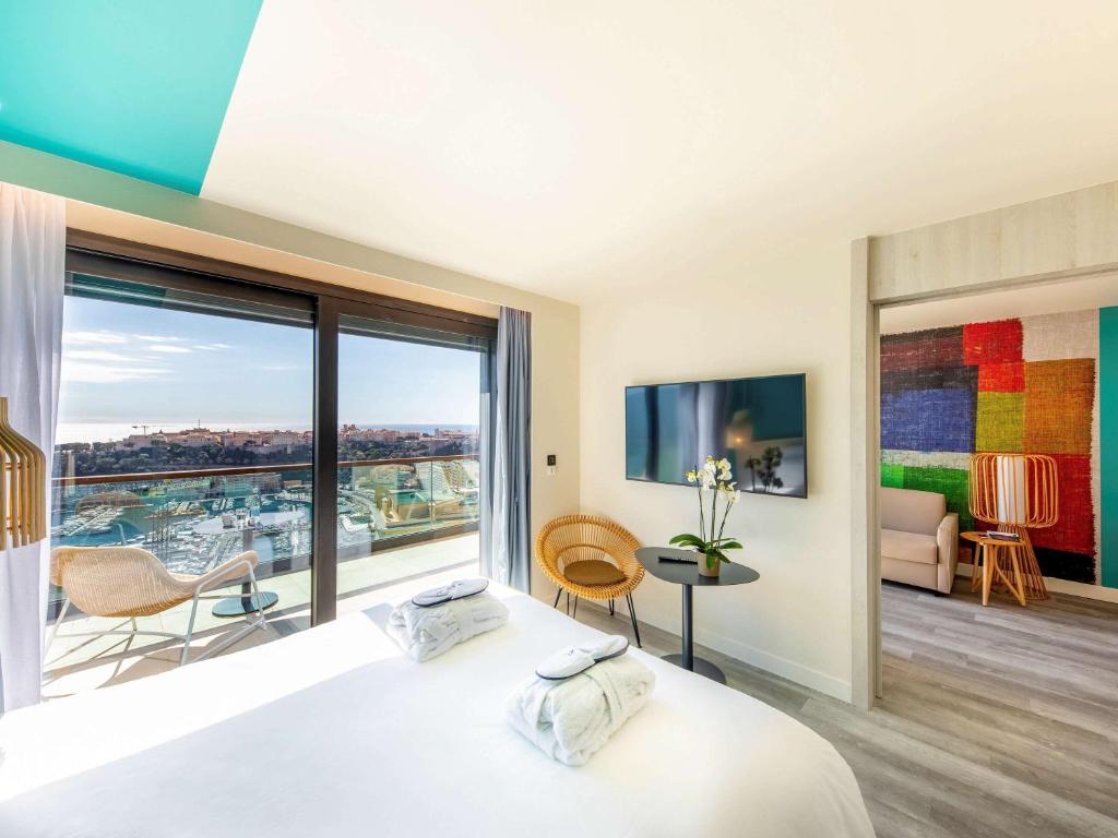 a bedroom with a bed and a large window at Novotel Monte-Carlo in Monte Carlo