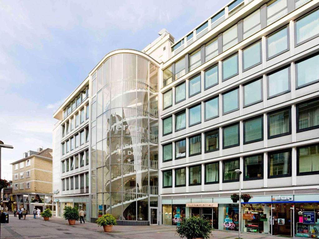 um edifício de vidro com pessoas a andar na frente dele em Mercure Hotel Aachen Am Dom em Aachen