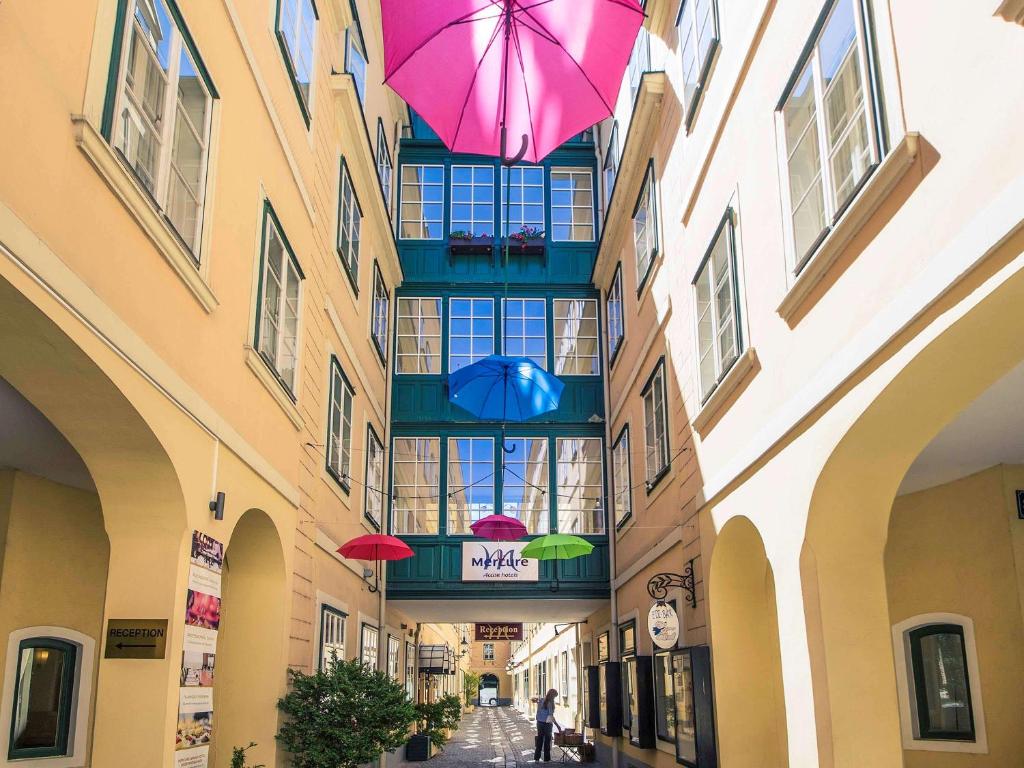 un callejón con sombrillas colgando de un edificio en Mercure Grand Hotel Biedermeier Wien en Viena