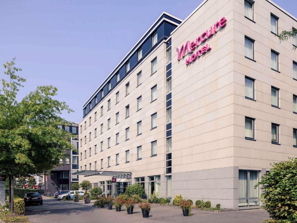 a large white building with a pink sign on it at Mercure Hotel Düsseldorf City Nord in Düsseldorf