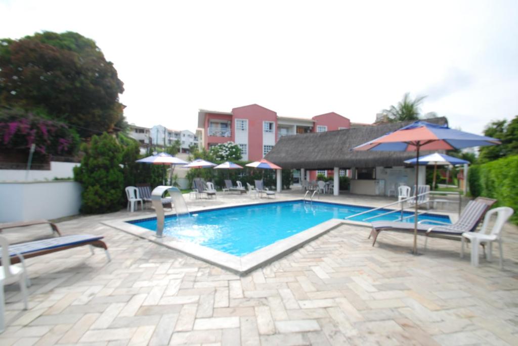 a swimming pool with chairs and umbrellas on a patio at Yatch Village Flat in Natal