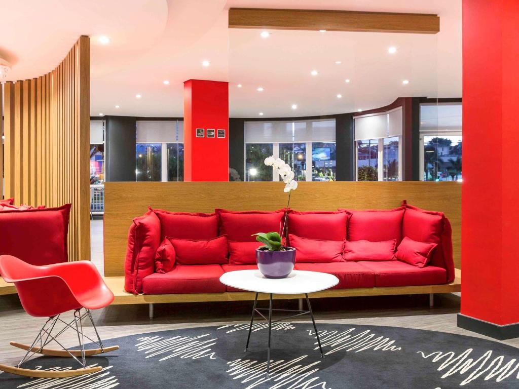 a red couch in a room with a table and chairs at ibis Sao Jose dos Campos Colinas in São José dos Campos