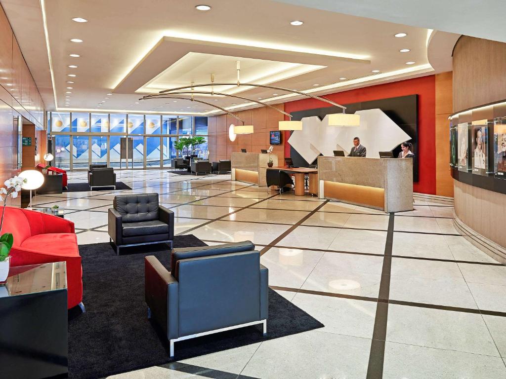 a lobby with chairs and a person at a desk at Novotel Sao Paulo Jaragua Conventions in Sao Paulo