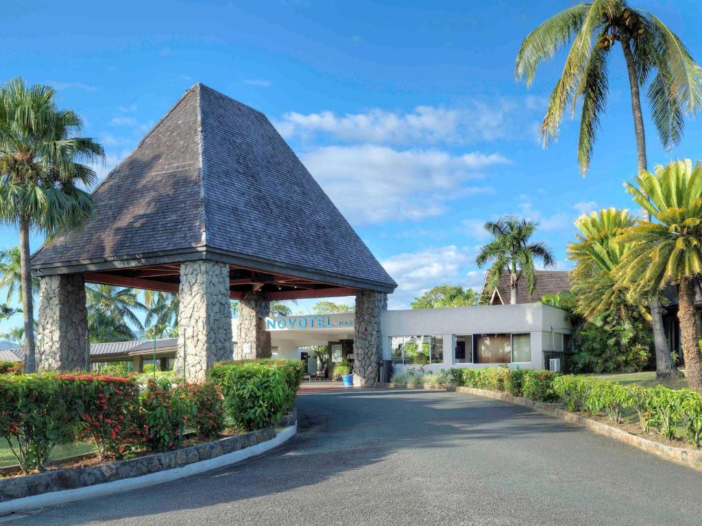 a building with a gazebo and palm trees at Novotel Nadi in Nadi