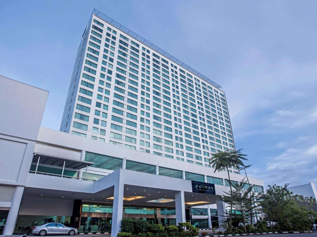 a tall building with a palm tree in front of it at Pullman Kuching in Kuching