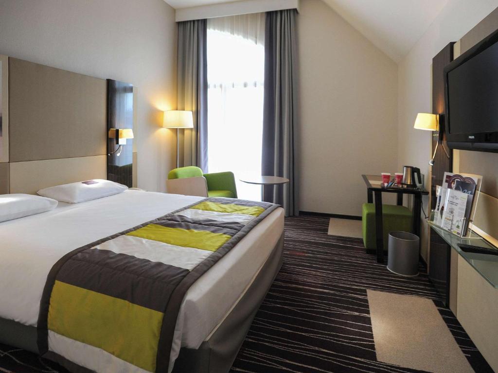 a hotel room with a large bed and a television at Mercure Granville Le Grand Large in Granville
