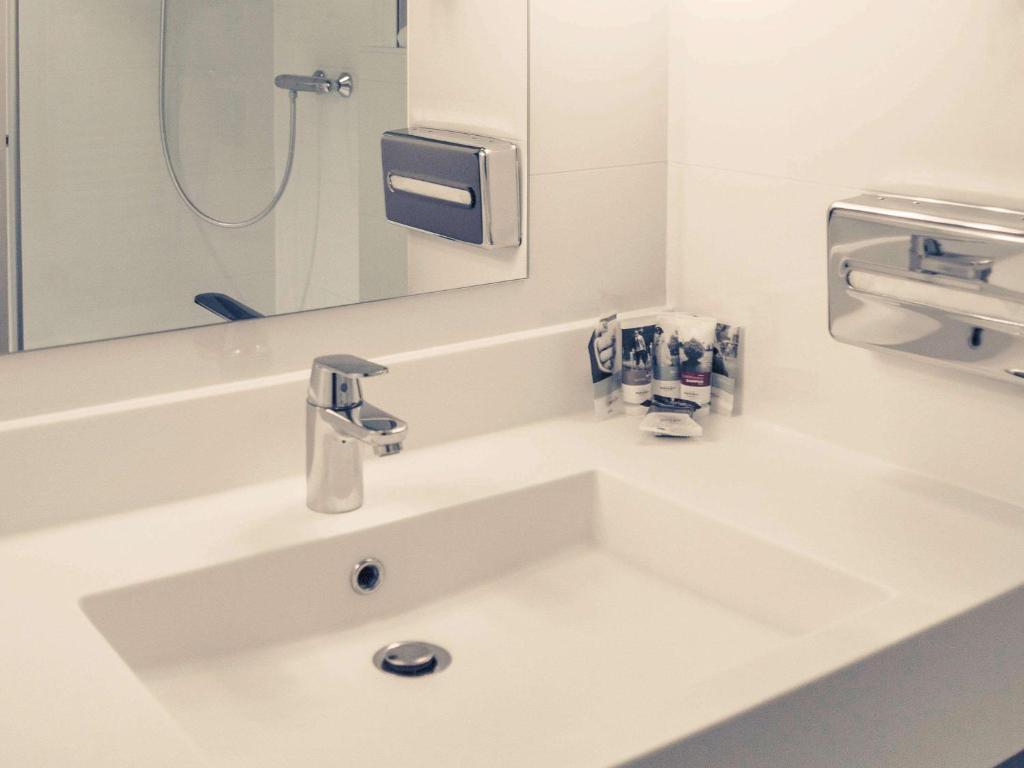 a white sink in a bathroom with a mirror at Mercure Granville Le Grand Large in Granville